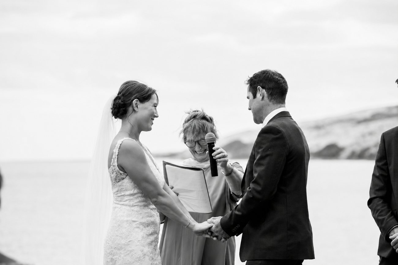 A couple holding hands through their vows with Chris reading beside them